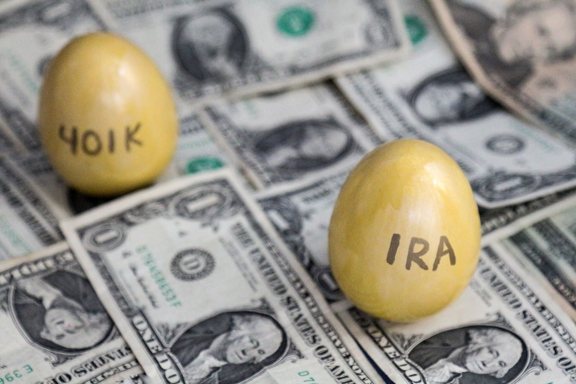 GOlden Eggs labeled with 401k and IRA sitting on money