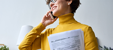 Professional woman on a phone holding papers.. Bruton, Nissen and Schellberg Taxes, Bookkeeping and Accounting firm located in Bellingham, WA.